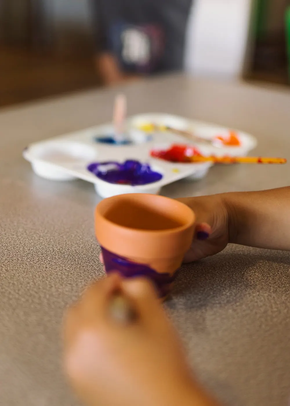A child painting a small terracotta pot