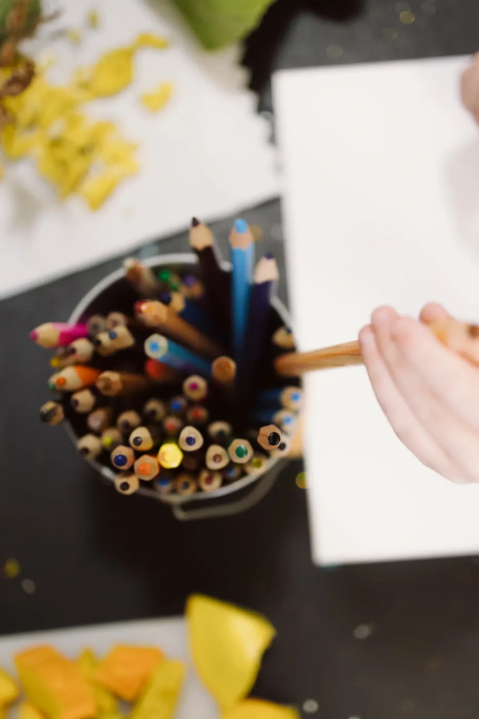 A child choosing a pencil from a jar of colours