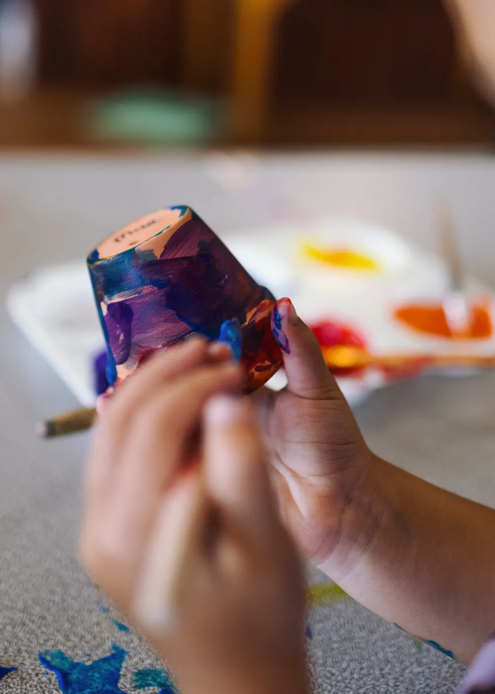 A child holding up a freshly painted pot